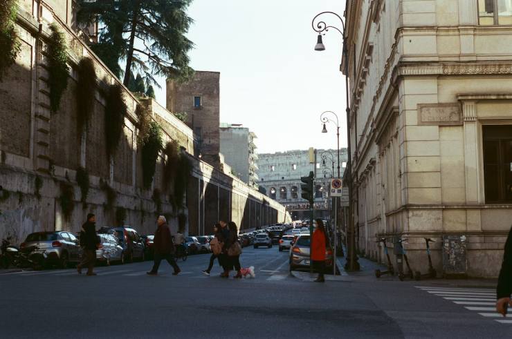 Strada di Roma con passanti e sullo sfondo il Colosseo