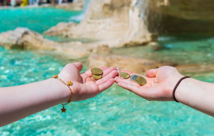 Mani con monete davanti alla fontana di Trevi a Roma